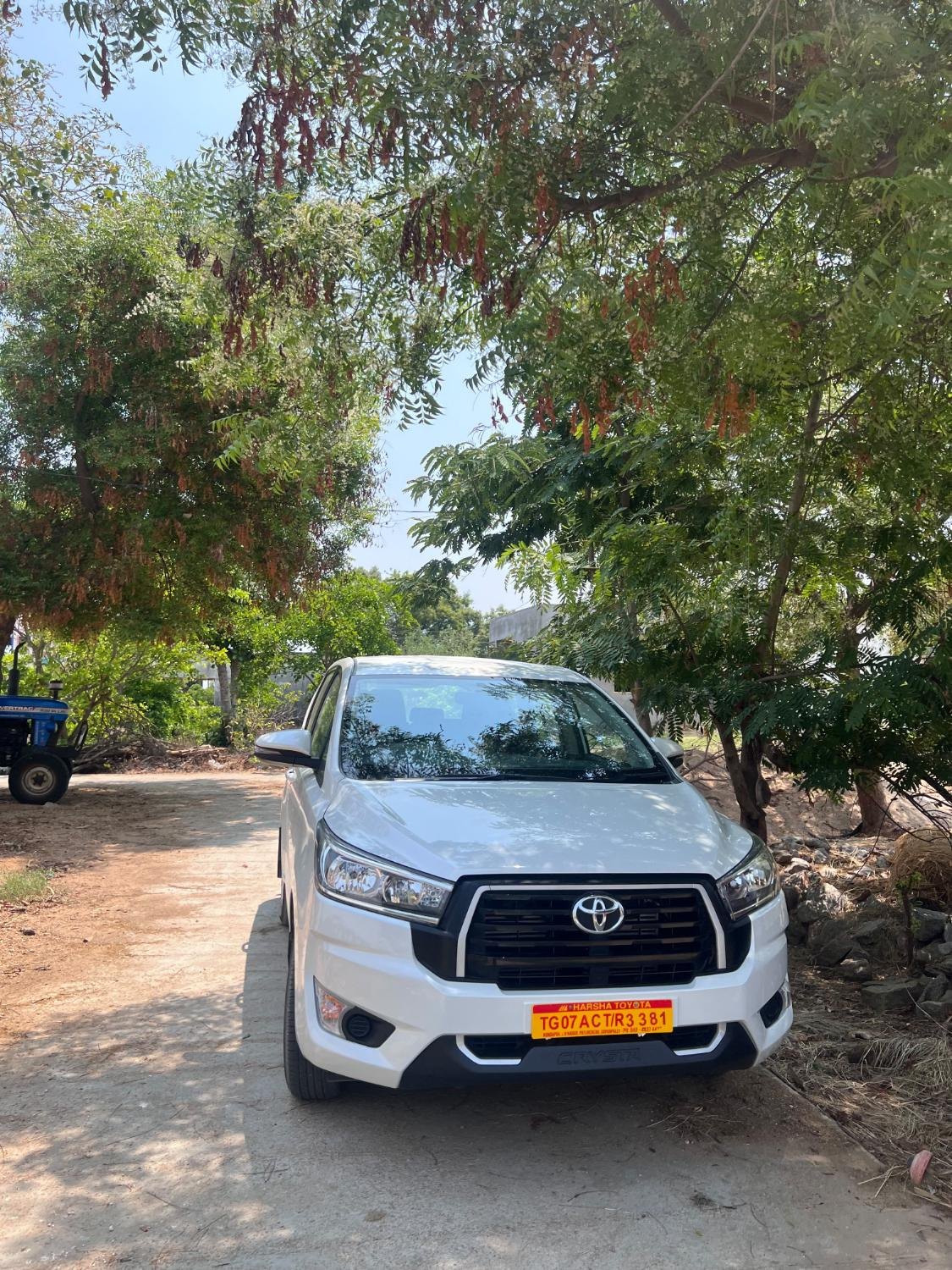 White Toyota Innova Crysta parked under trees